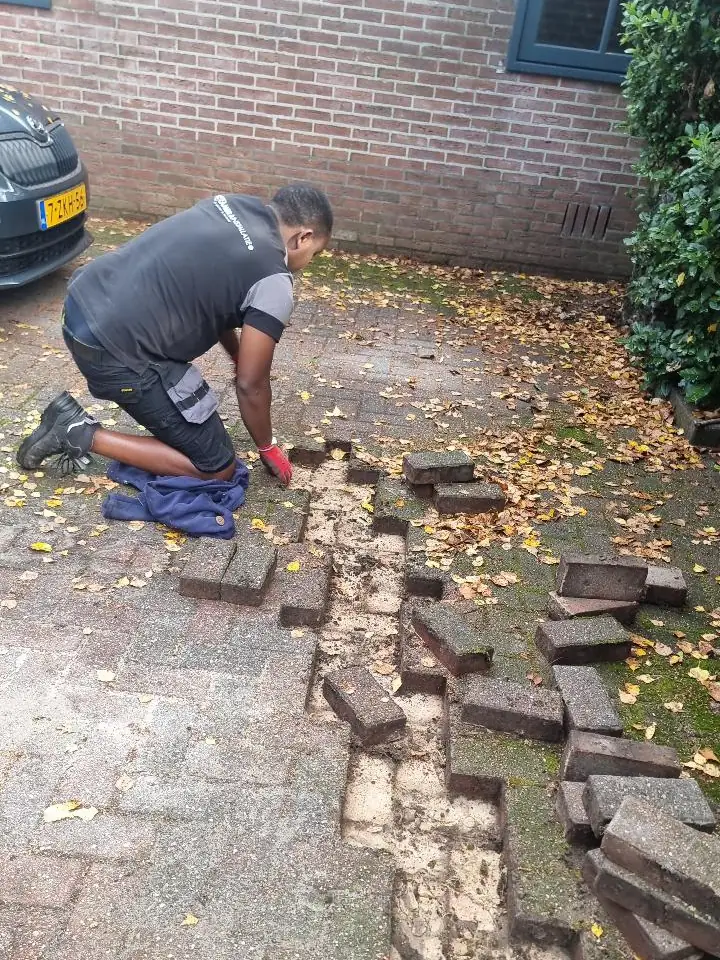 De bestrating wordt teruggelegd nadat de sleuf is gedicht