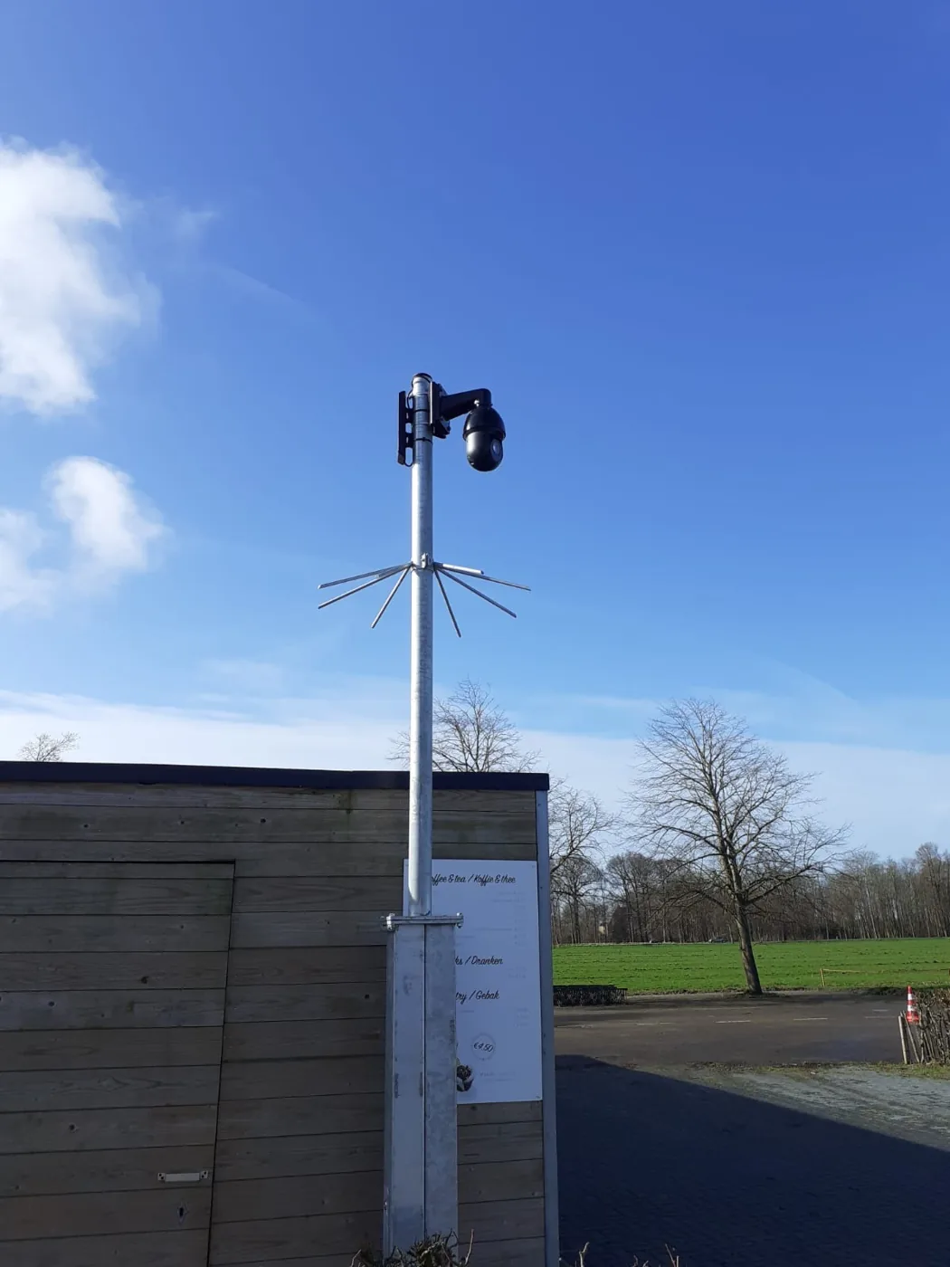 Camerapaal aan de rand van een parkeerterrein bij een sportcomplex