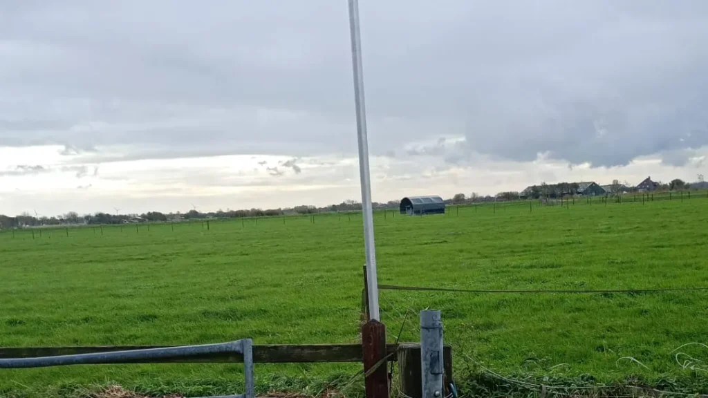 Camerapaal in een weiland, vlak bij het hek en het toegangspad