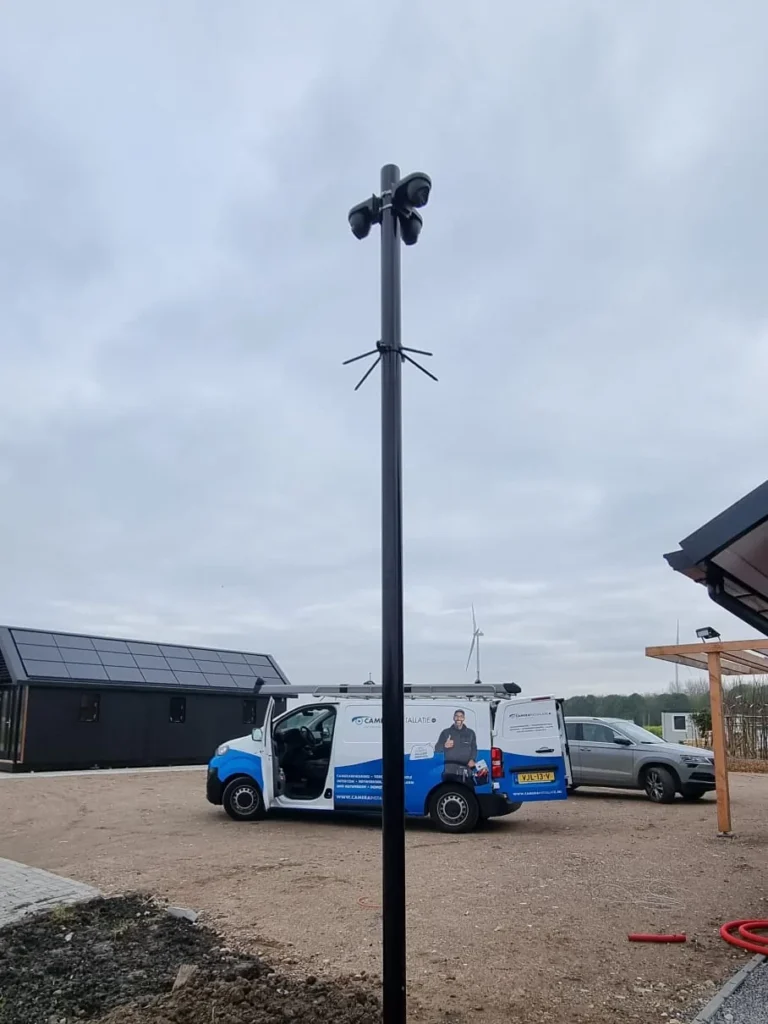 Camerapaal met meerdere camera’s rondom, afgetekend tegen een bewolkte lucht
