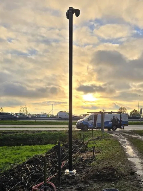 Camerapaal tegen de avondlucht boven het veld, aan het eind van de werkdag