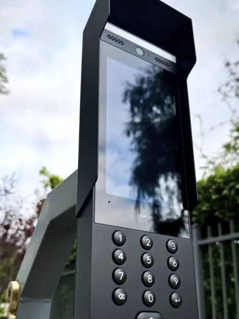 Intercom met scherm en toetsenbord op een paal naast het toegangshek