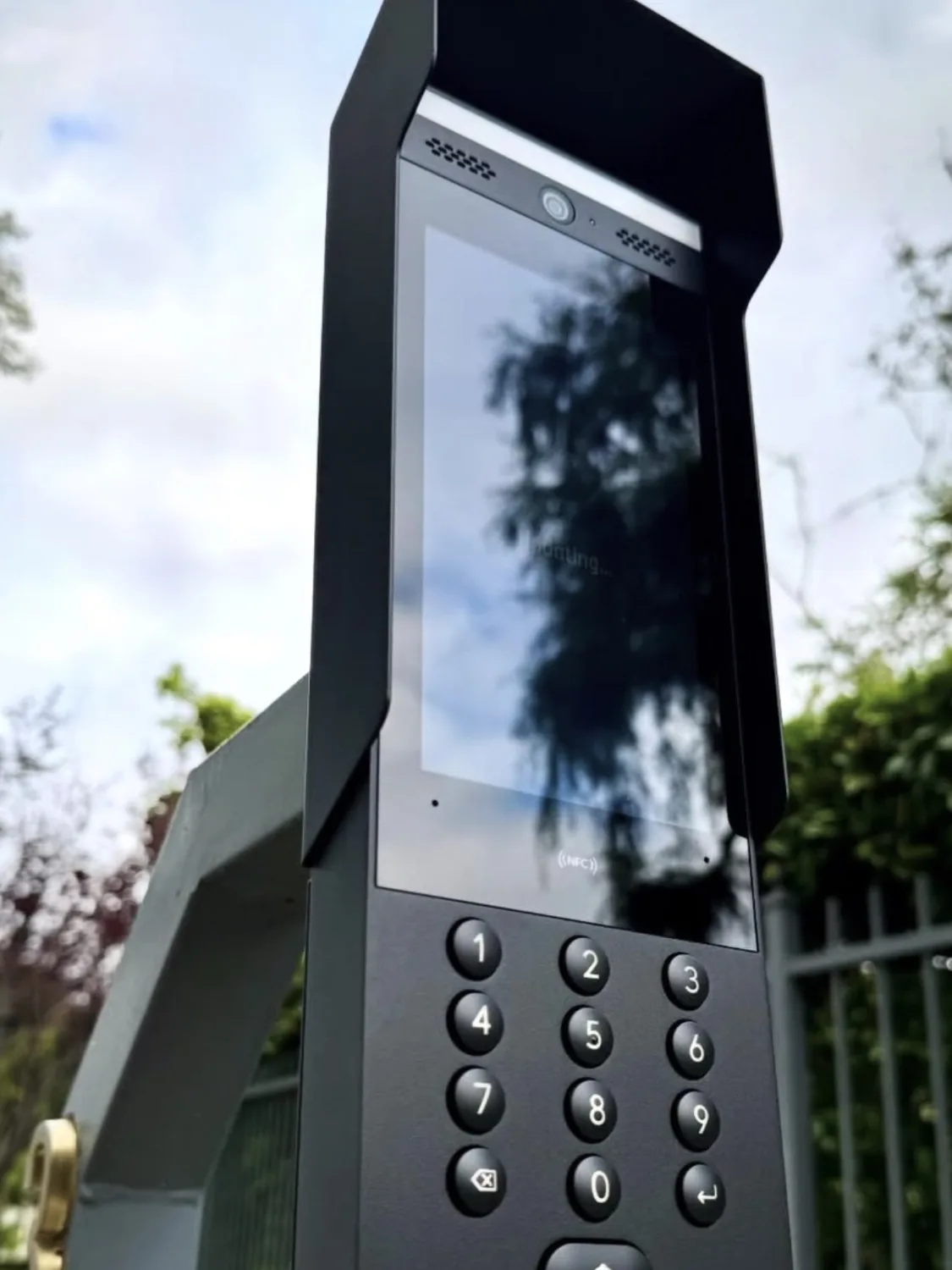 Intercom met scherm en toetsenbord op een paal naast het toegangshek