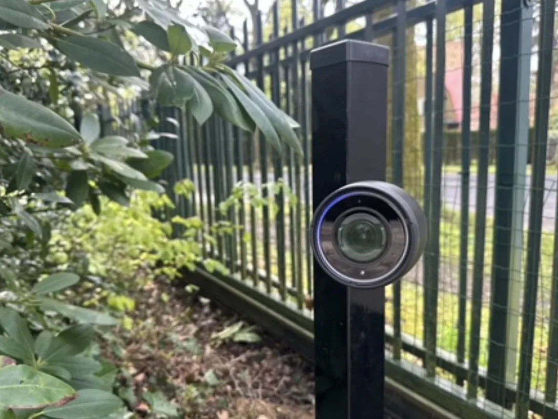 Laag zwart camerapaaltje bij de inrit, met de camera recht op de rijrichting