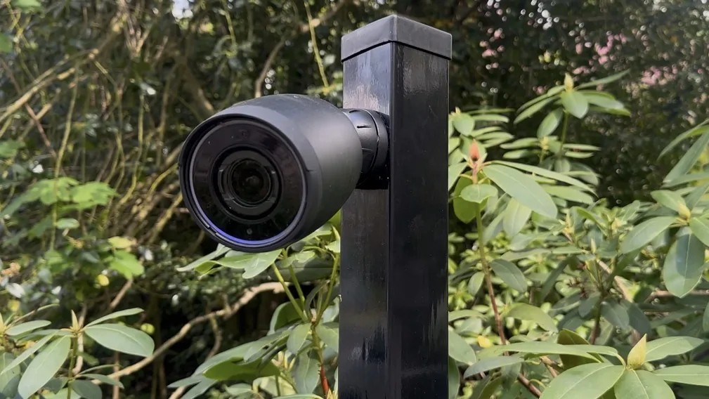 Laag camerapaaltje met een camera op ooghoogte, weggewerkt tussen de beplanting