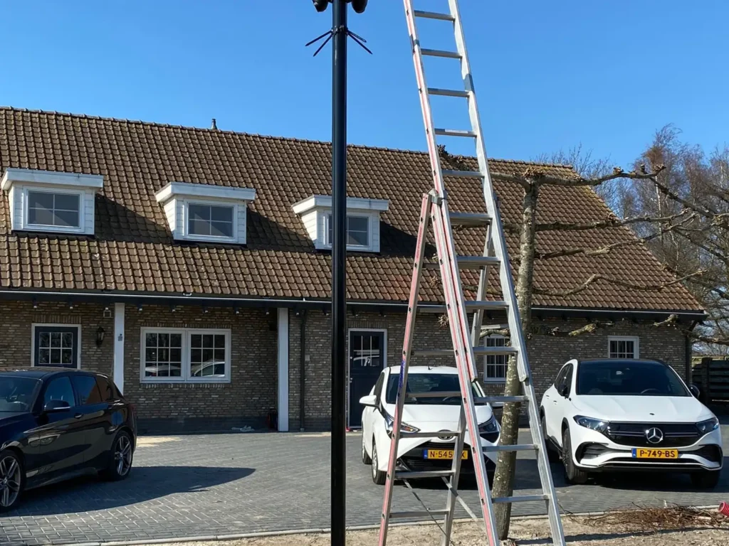 Ladder tegen een camerapaal bij een woning, tijdens de installatie