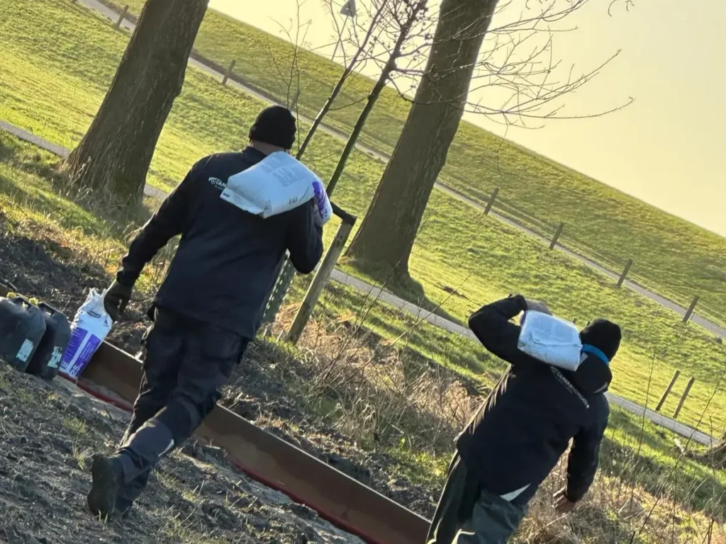 Monteurs die het materiaal over het terrein naar de plek van de paal brengen