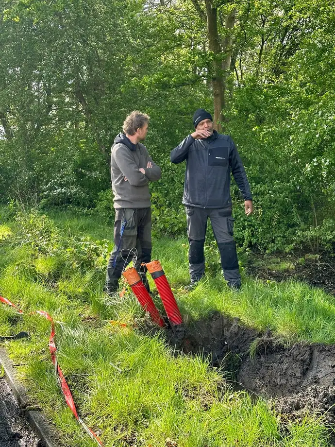 Twee monteurs bij de open sleuf, voordat de mantelbuis erin gaat