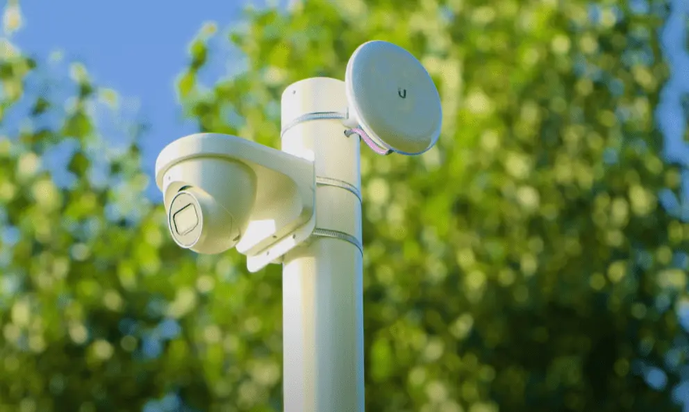Witte mast met een draaibare camera en een straalzender