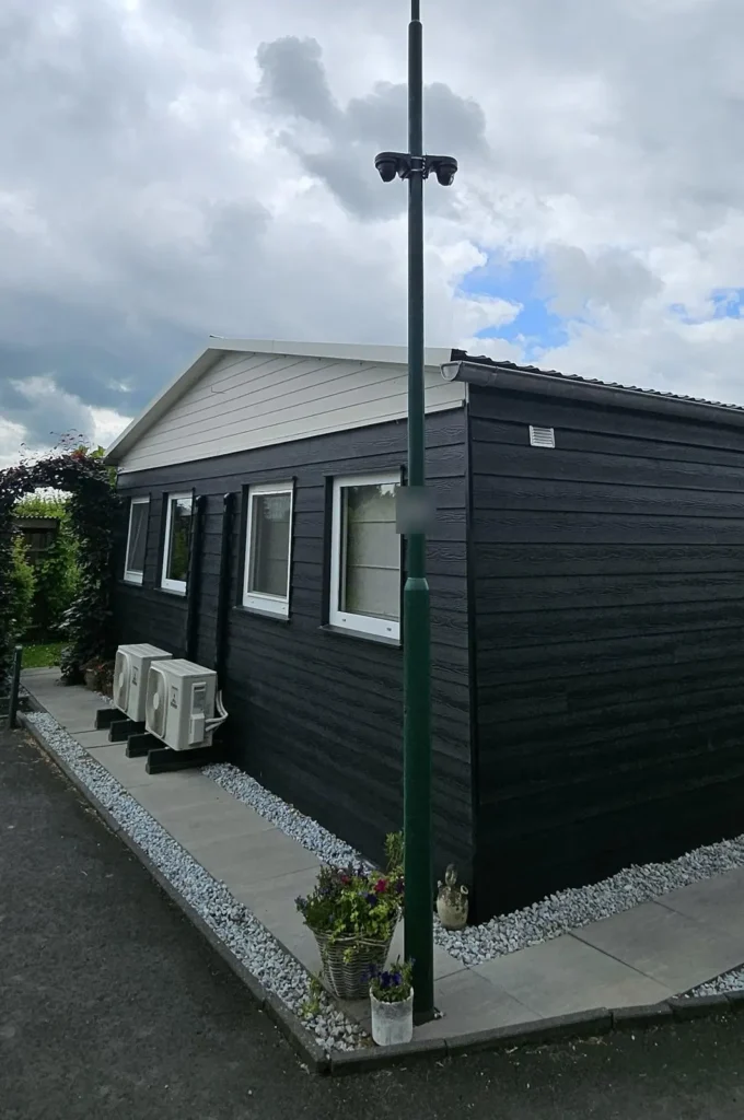 Mast met twee camera’s bij een zorgwoning op een erf