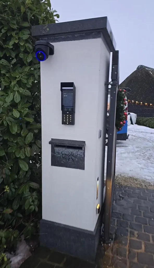 Witte zuil bij de oprit met camera, intercom en brievenbus