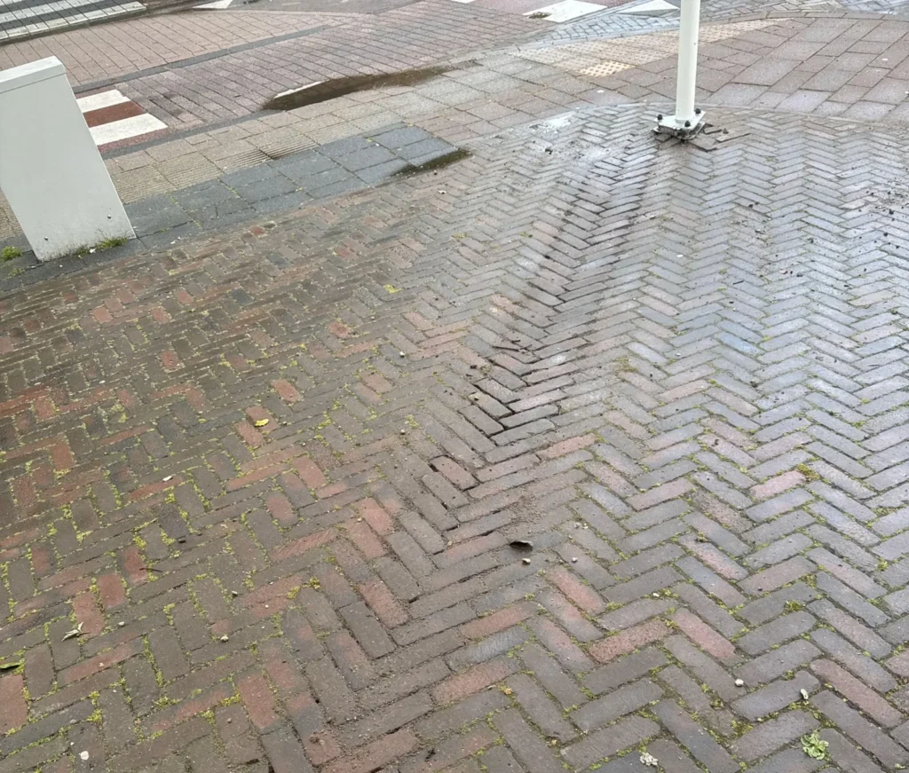 Voet van de vlaggenmast in de bestrating, met de kabel onder de stoep