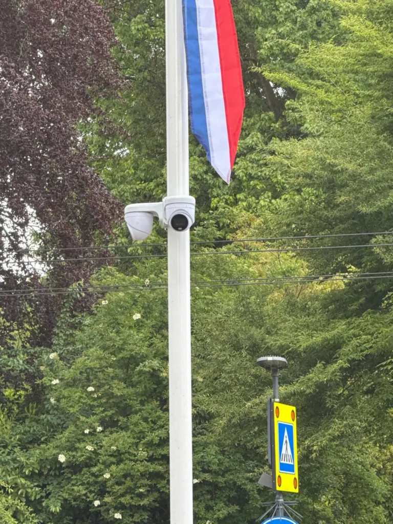Twee witte camera’s onder de vlag halverwege een witte vlaggenmast