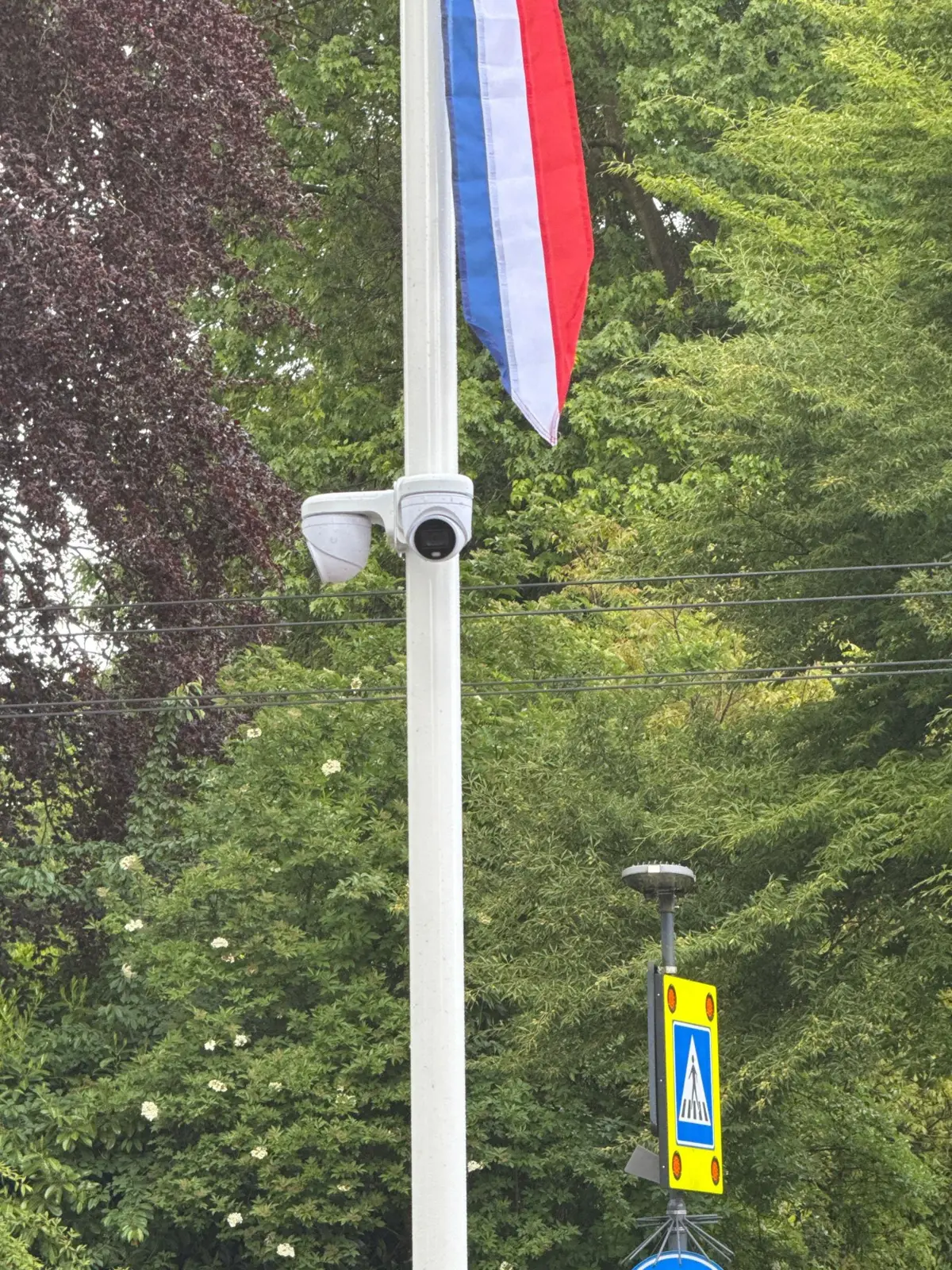 Twee witte camera’s onder de vlag halverwege een witte vlaggenmast