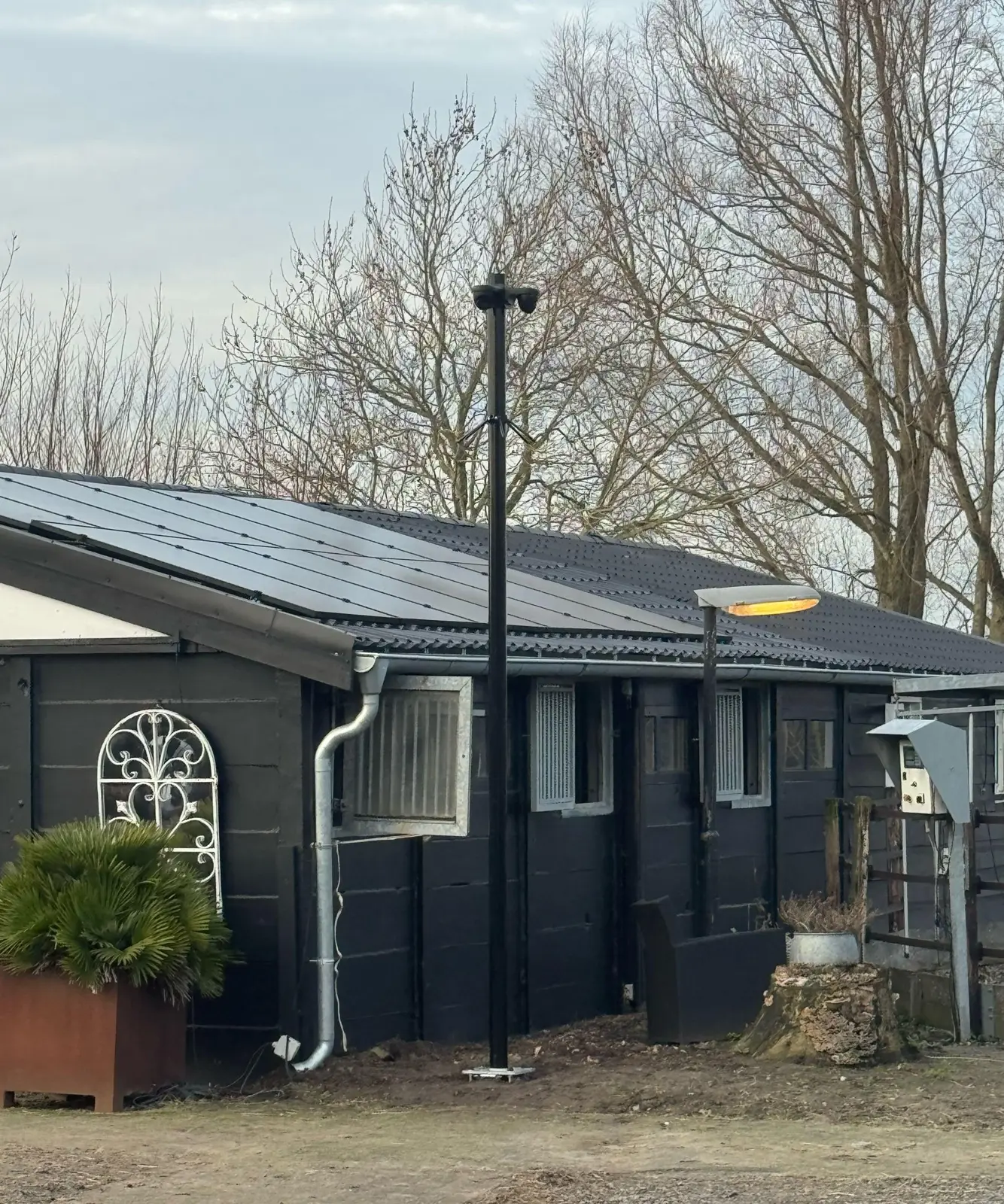 Zwarte cameramast van vier meter naast een paardenstal